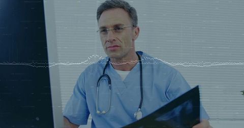Experienced clinician reviewing x-ray on monitor wearing blue scrubs and stethoscope