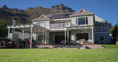Two-story home sitting at mountain base, featuring solar panels and wide wooden deck