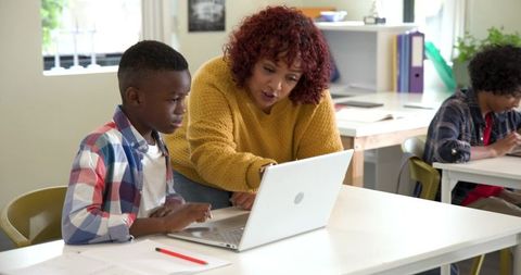 Teacher guiding student on laptop for educational success