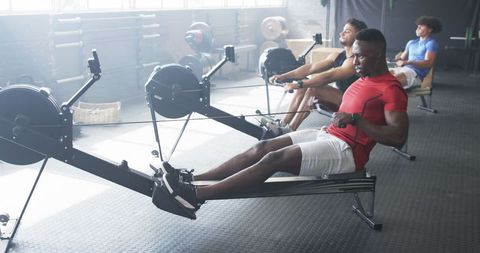 Diverse group of young men exercising on rowing machines