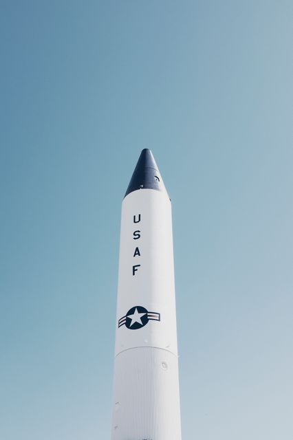 Vertical format close-up of a USAF missile against a clear blue sky. Suitable for use in defense technology articles, military-themed projects, aerospace studies, and patriotic imagery.