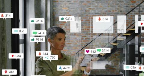 Mature professional woman using tablet in modern loft with live social notifications