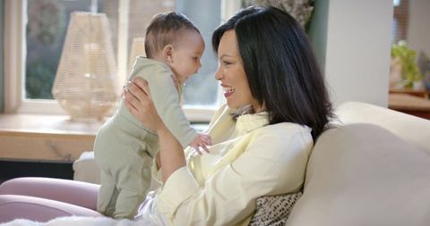 Mother and infant daughter bonding in sunlit living room