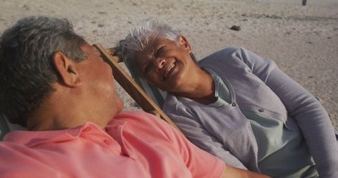 Happy Elderly Couple Relaxing on Beach at Sunset