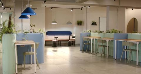 Modern minimalist coworking lounge with blue booths, pendant lights and indoor plants