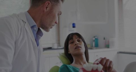 Dentist Consultation with Patient Holding Dental Model in Clinic