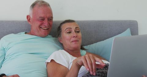 Senior Couple Relaxing With Laptop at Home in Bedroom
