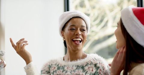 Diverse friends laughing and chatting in cozy holiday knitwear with santa hats