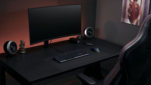 Minimal black gaming desk with curved monitor, rgb backlit keyboard and ergonomic chair