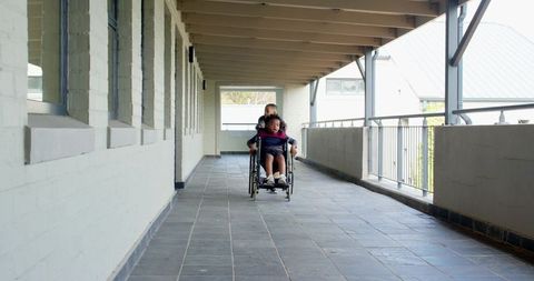 Young friends exploring corridor with wheelchair ride