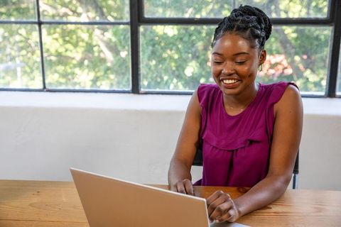 Smiling Woman Typing on Laptop in Modern Home Office