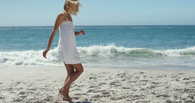This image captures a carefree moment of a young woman walking along a sandy beach, barefoot, while enjoying the sunny outdoors. Ideal for use in travel and tourism promotions, summer vacation advertising, lifestyle blogs, and wellness content. It evokes feelings of relaxation, freedom, and connection with nature.