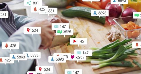 Senior Indian Homecook Chopping Scallions on Wooden Board Surrounded by Social Notifications