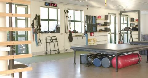 Rehabilitation clinic treatment table with foam rollers and mobility equipment in therapy room