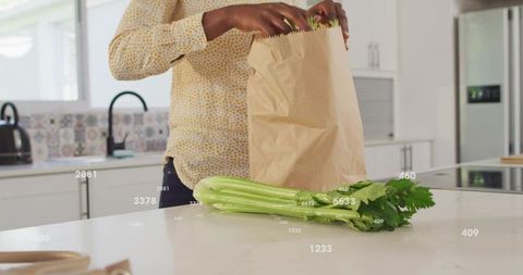 Unpacking groceries placing fresh celery on bright modern kitchen island for meal prep