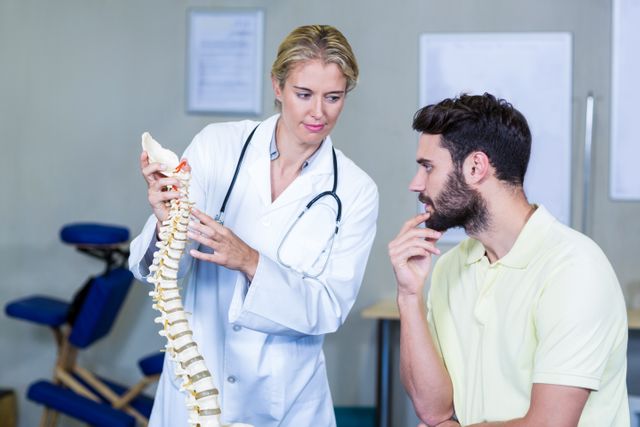 Physiotherapist explaining spine model to patient - Download Free Stock Photos Pikwizard.com