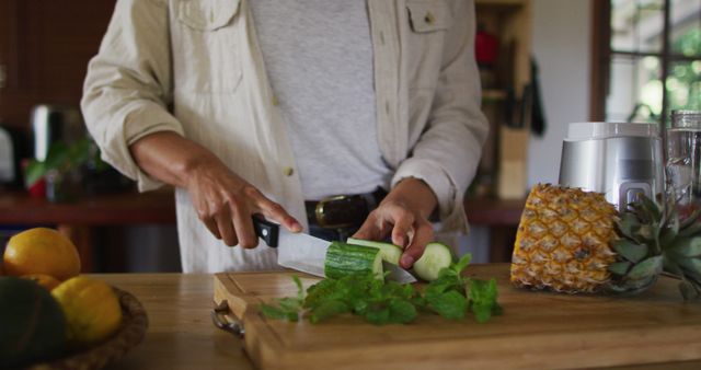 Person chopping cucumber with knife in modern kitchen - Download Free Stock Images Pikwizard.com