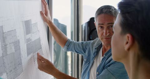 Architects Analyzing Building Blueprint in Modern Office