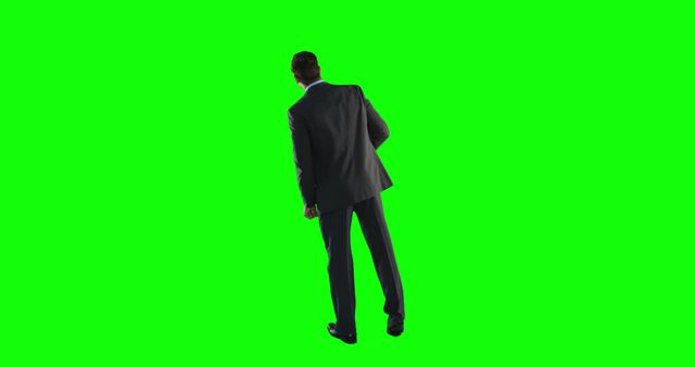 Professional businessman standing in formal suit shown from behind on a green screen background. Ideal for use in promotional materials, business presentations, advertisements or any creative projects involving green screen effects.