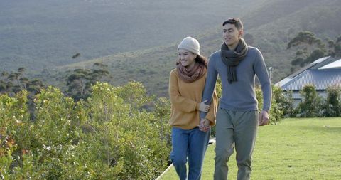 Asian Couple Strolling Hand in Hand in Scenic Countryside