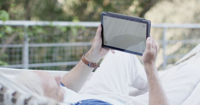 Older man relaxing on hammock and reading tablet outdoors - Download Free Stock Images Pikwizard.com