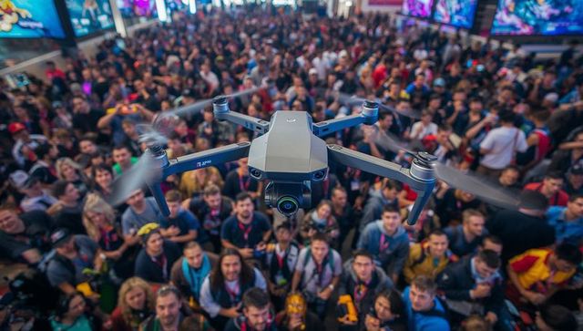 Hovering drone capturing crowded expo floor with camera gimbal, rotating propellers