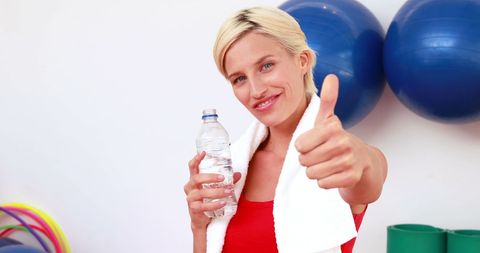 Caucasian woman embracing fitness and hydration in gym