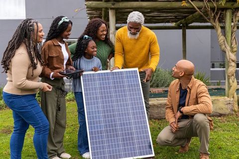 African american multigenerational family exploring solar panel energy in backyard