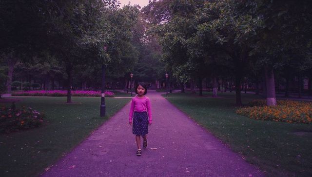 Child walking on park path during purple dusk twilight