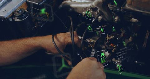 Mechanic using digital diagnostics on car engine with neon icons