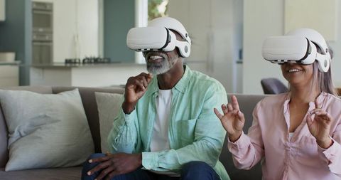 Senior couple wearing VR headsets enjoying immersive virtual reality experience at home