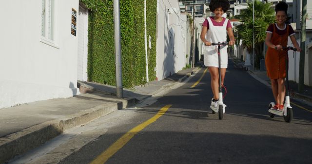 Two Young Women Riding Electric Scooters Down Urban Street - Download Free Stock Images Pikwizard.com