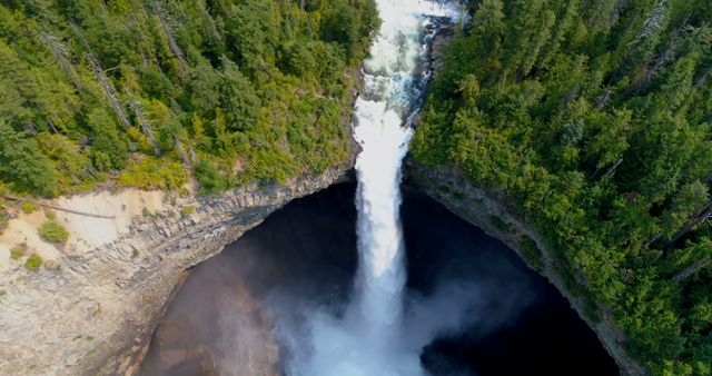 This stunning aerial perspective captures a waterfall plunging dramatically into a gorge, surrounded by lush, dense forest. Ideal for use in travel and adventure blogs, environmental websites, nature magazines, and promotional materials showcasing the beauty of the wilderness. Perfect for illustrations of Canadian landscapes and natural wonders.