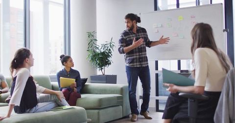 Presenting team leader facilitating creative brainstorming session in modern office lounge