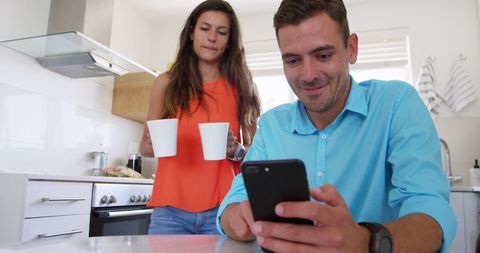 Couple in Kitchen with Man Engaging Smartphone - Download Free Stock Images Pikwizard.com