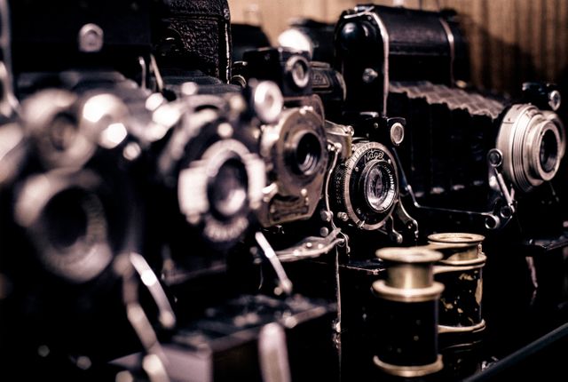 Vintage cameras and film reels arranged on display, suitable for use in themes of photography history, nostalgia, and collectibles. Ideal for illustrating retro photography, antique displays, hobby interests, or timeless technology.