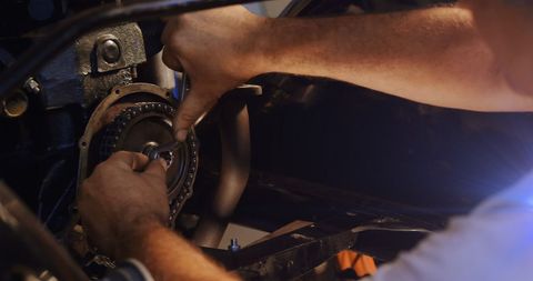 Caucasian mechanic fixing car engine with tools