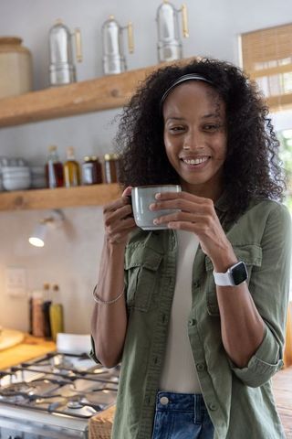 African american woman enjoying morning coffee in modern cozy kitchen
