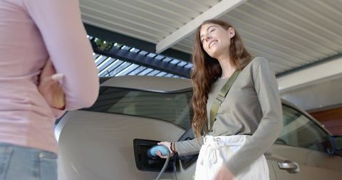 Friends Charging Electric Car in Carport Emphasizing Eco-Friendly Living