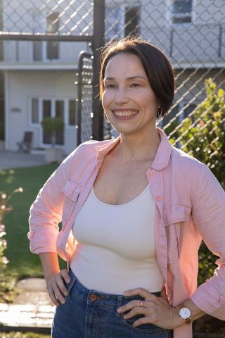Cheerful woman smiling in sunny residential courtyard