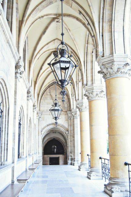 Depicts historic gothic corridor with impressive vaulted ceiling and antique lamp posts. Ideal for promoting historical tours, educational content on gothic architecture, or adding classic architectural elements to wallpapers and brochures.