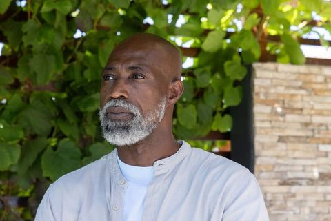 Mature african american man looking left, thoughtful outdoor portrait on leafy garden patio