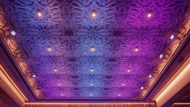 Ornate coffered ceiling with embossed floral molding and purple-amber LED wash lighting