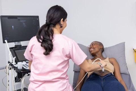 Clinician performing abdominal ultrasound on smiling patient in modern medical exam room
