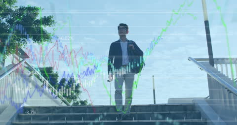 Asian businessman walking in urban area with digital graphs overlay illustrating financial data, suggesting dynamic interaction between business and technology. Use in contexts involving stock market, financial analysis, futuristic business concepts, global economics, or corporate environment innovation and strategy.