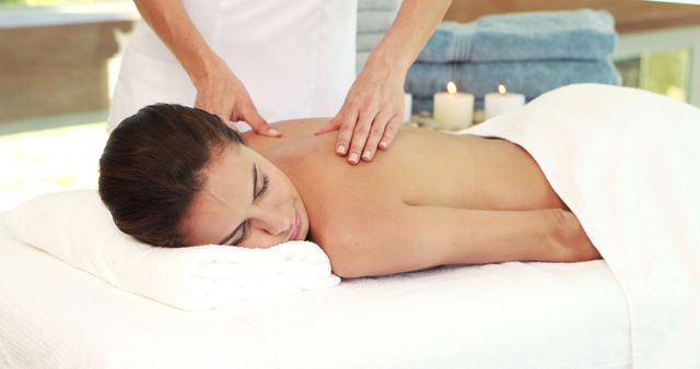 A young Caucasian woman enjoys a relaxing back massage from a therapist in a serene spa environment, with copy space. Such wellness treatments are popular for stress relief and promoting mental and physical health.