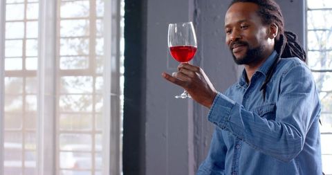 Man Enjoying Glass of Red Wine in Modern Office Space