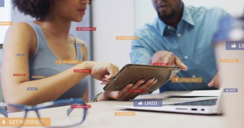 Colleagues Collaborating on Tablet Showing Social Media Notifications and Like Overlays