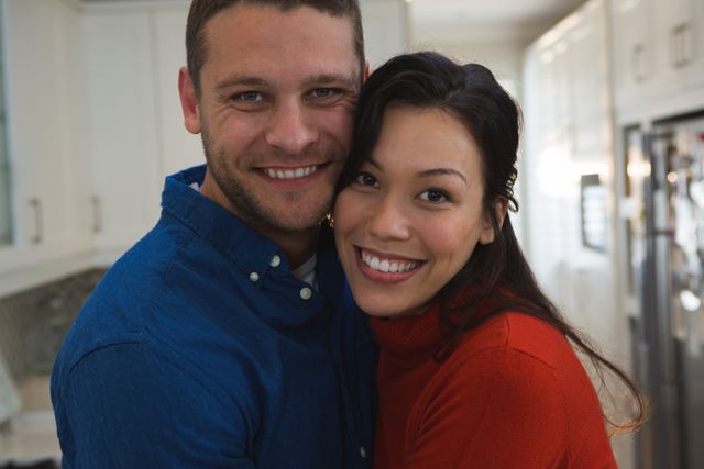 Couple embracing and smiling in a cozy home environment. Perfect for use in advertisements, relationship blogs, lifestyle articles, and social media posts promoting love, happiness, and domestic life.