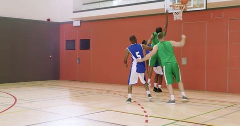 African american player driving to basket and rebounding while teammates contest shot